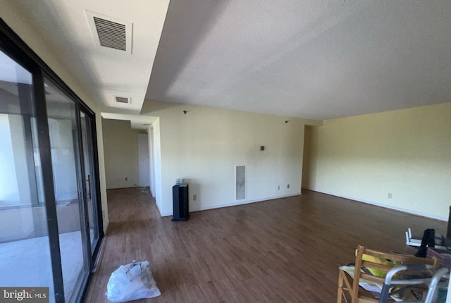 unfurnished living room with dark wood-type flooring and a textured ceiling