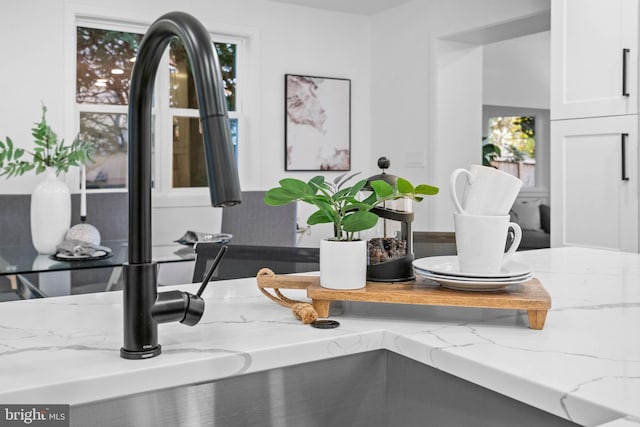 details featuring white cabinetry and light stone countertops