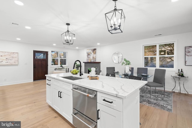 kitchen featuring light hardwood / wood-style flooring, white cabinetry, a kitchen island with sink, and sink