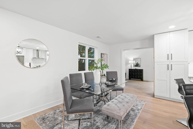 dining area with light hardwood / wood-style flooring and a notable chandelier