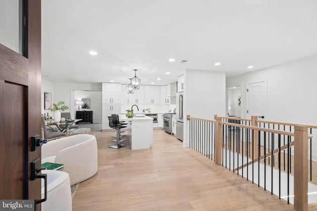 living room featuring a chandelier, sink, and light hardwood / wood-style floors