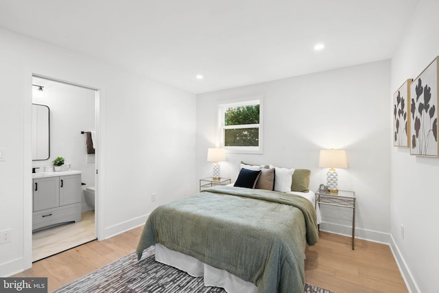 bedroom with connected bathroom and hardwood / wood-style floors