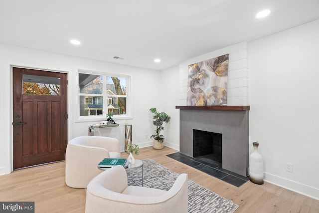 living room with light wood-type flooring and a large fireplace