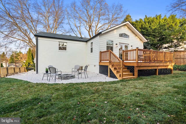 back of house featuring a lawn, a fire pit, and a deck