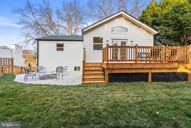 back of house featuring an outdoor fire pit, a lawn, and a wooden deck