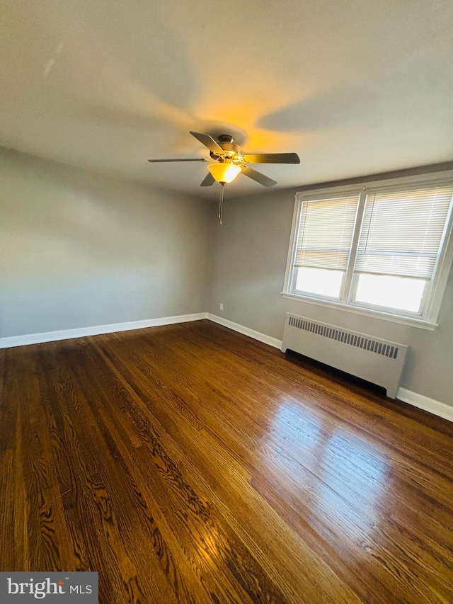 unfurnished room with radiator, ceiling fan, and dark hardwood / wood-style flooring