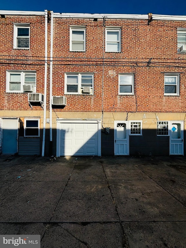 rear view of property featuring cooling unit and a garage