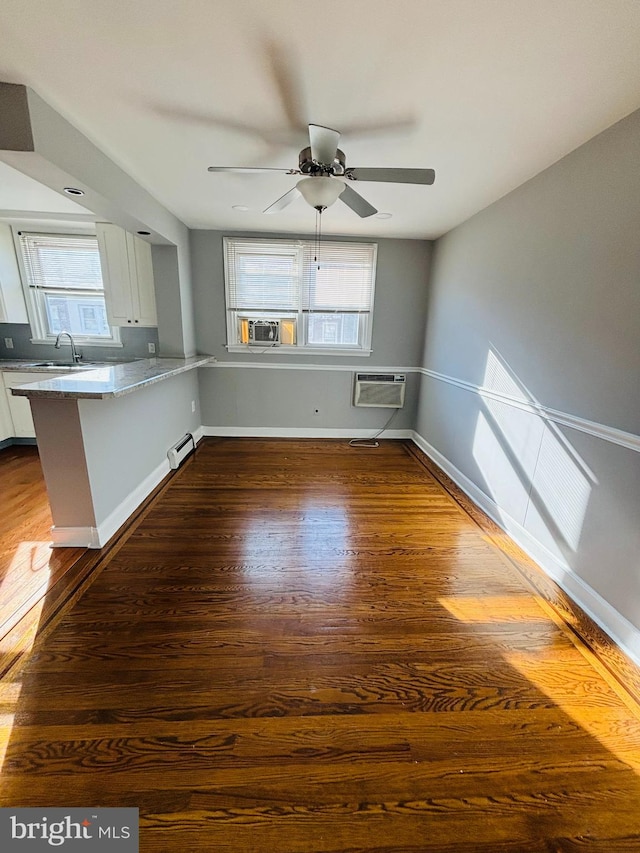 interior space with dark hardwood / wood-style floors, a healthy amount of sunlight, sink, and a wall unit AC