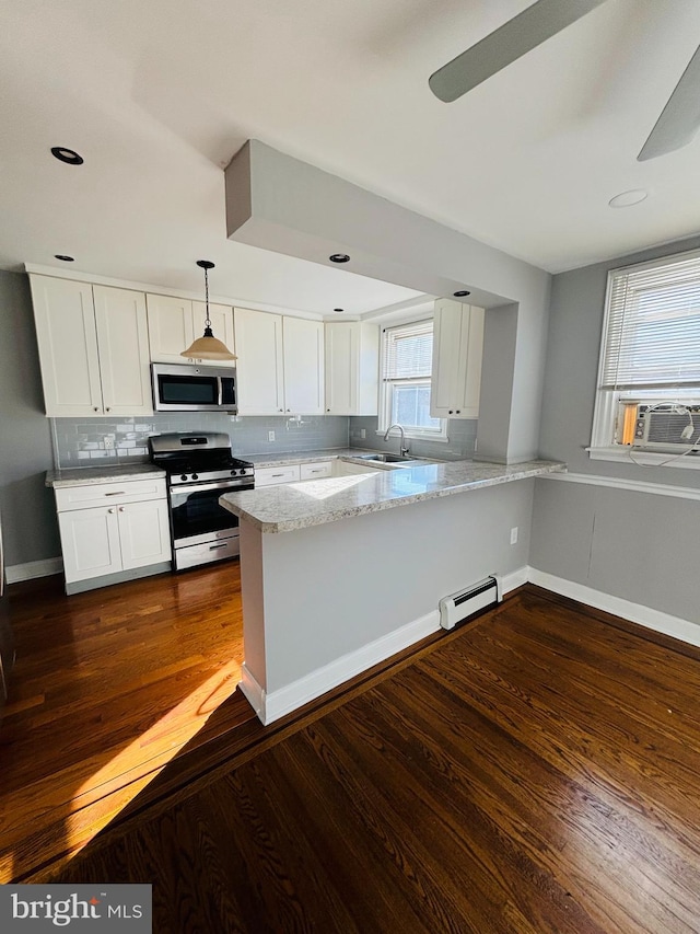 kitchen with kitchen peninsula, dark hardwood / wood-style flooring, pendant lighting, and appliances with stainless steel finishes