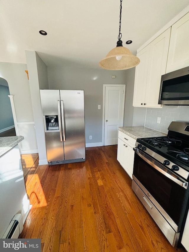 kitchen featuring light stone countertops, appliances with stainless steel finishes, white cabinets, and dark wood-type flooring