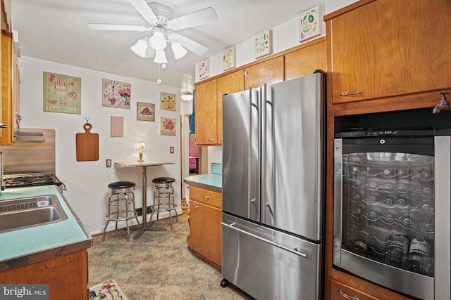 kitchen featuring stainless steel refrigerator, ceiling fan, sink, and beverage cooler