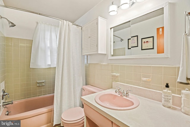 full bathroom with shower / bath combo, toilet, tile walls, and vanity