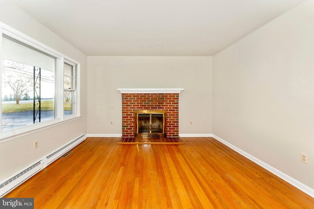 unfurnished living room featuring baseboard heating, a fireplace, and wood-type flooring