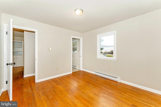 unfurnished bedroom featuring a closet, a baseboard radiator, and hardwood / wood-style flooring