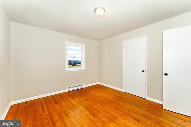 unfurnished room with hardwood / wood-style floors and baseboard heating