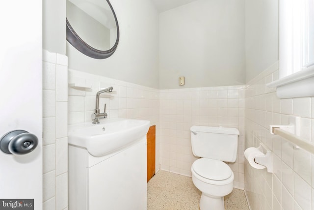 bathroom with vanity, toilet, and tile walls