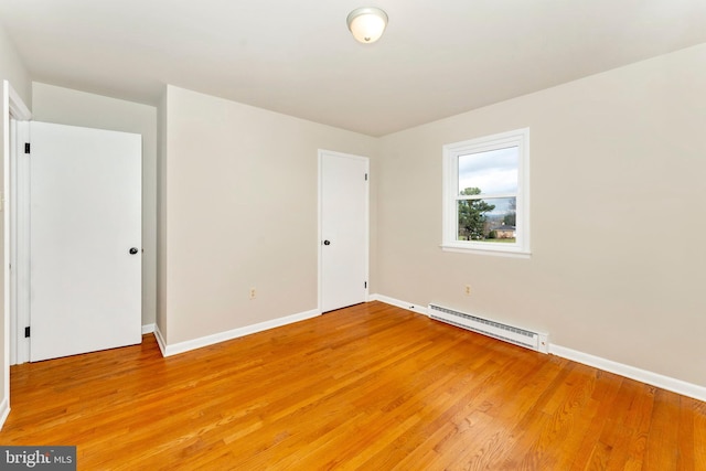 unfurnished room featuring baseboard heating and light wood-type flooring