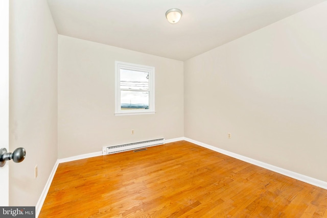 empty room featuring baseboard heating and wood-type flooring