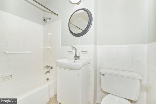 full bathroom featuring vanity, toilet, tile walls, and tiled shower / bath