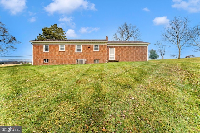 back of house with central AC unit and a lawn