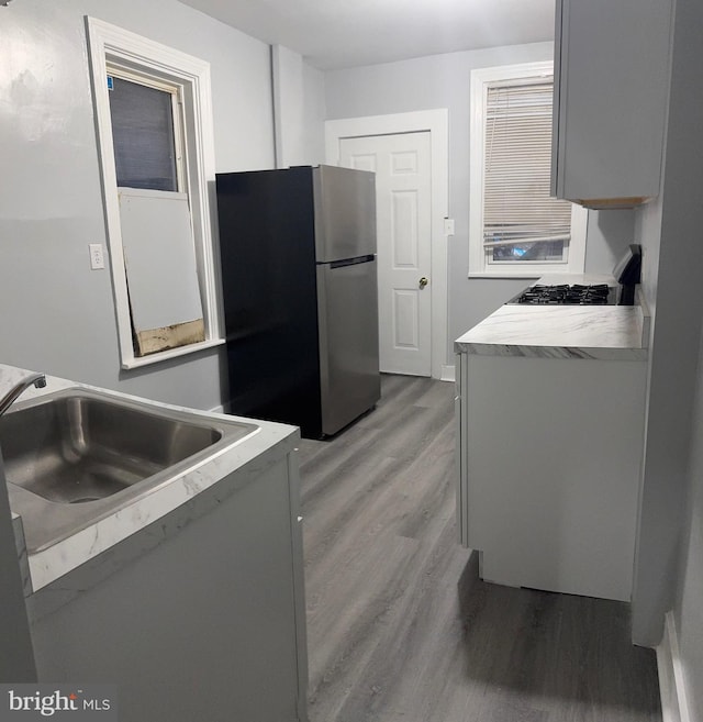 kitchen featuring wood-type flooring, stainless steel refrigerator, and sink