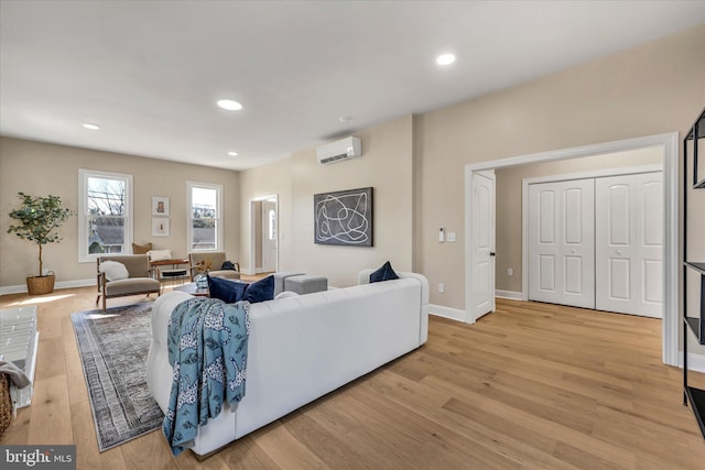 living room featuring a wall mounted air conditioner and light hardwood / wood-style floors