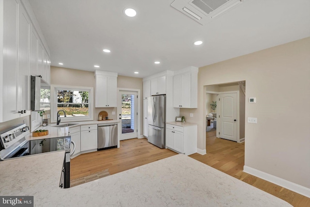 kitchen featuring white cabinetry, sink, stainless steel appliances, and light wood-type flooring