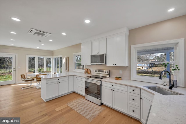 kitchen with a healthy amount of sunlight, white cabinetry, sink, and appliances with stainless steel finishes