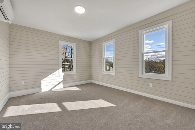 spare room with a wall mounted AC, wood walls, and carpet floors