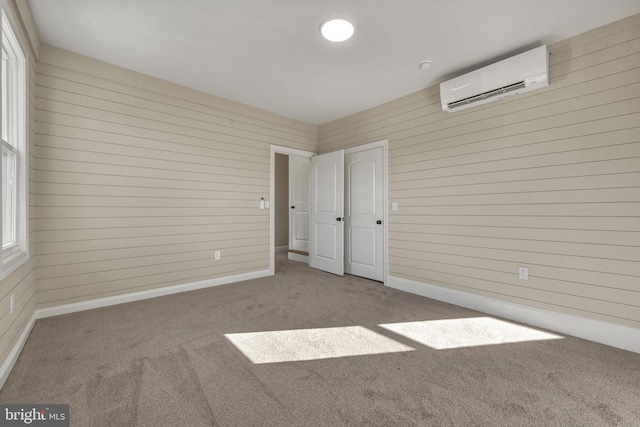 unfurnished bedroom with a wall mounted air conditioner, light carpet, and wood walls