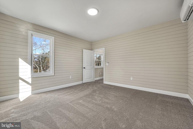 empty room with a wall unit AC, wood walls, and carpet flooring