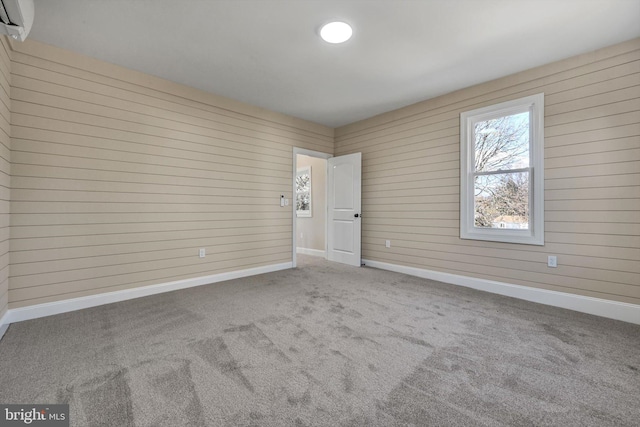 empty room with carpet and wood walls