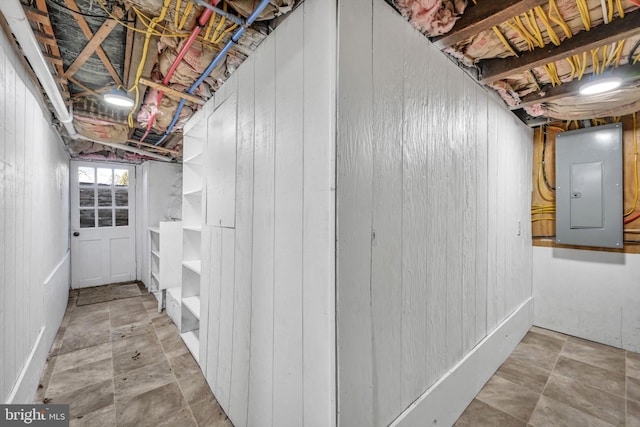 basement featuring electric panel and wooden walls