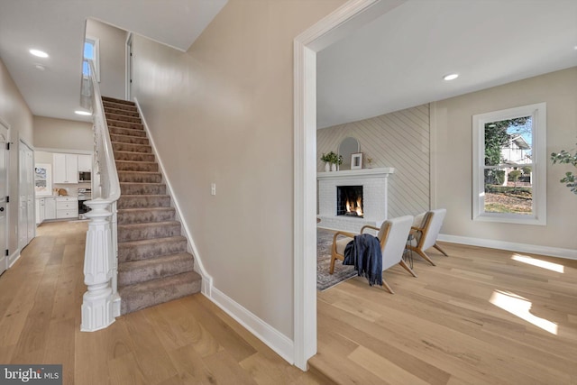 stairs with a fireplace and wood-type flooring