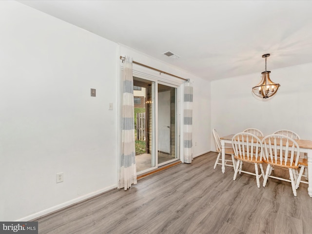 dining room with light wood-type flooring and an inviting chandelier