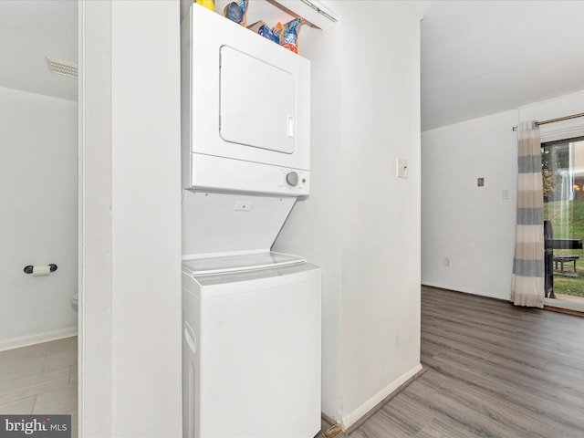 washroom featuring hardwood / wood-style floors and stacked washer and dryer