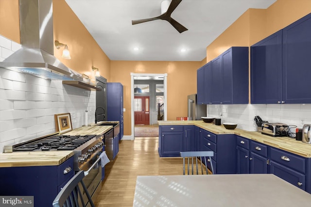 kitchen with backsplash, blue cabinets, high end stainless steel range oven, wall chimney exhaust hood, and light wood-type flooring