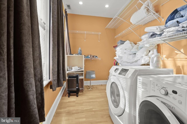 laundry area featuring radiator heating unit, light wood-type flooring, and independent washer and dryer