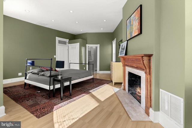 bedroom featuring a premium fireplace and light wood-type flooring