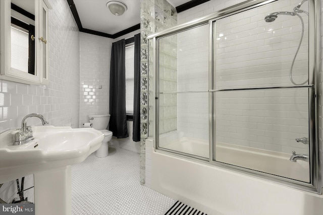 full bathroom featuring crown molding, bath / shower combo with glass door, tile walls, and toilet