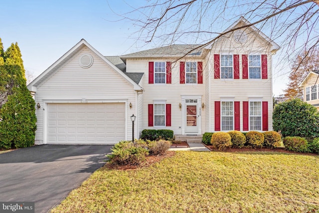 view of front of property featuring an attached garage, aphalt driveway, and a front yard