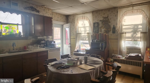 dining area with a paneled ceiling, cooling unit, radiator heating unit, and sink