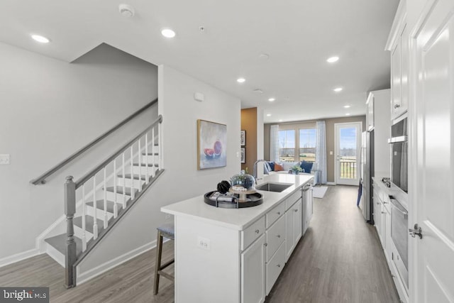 kitchen featuring a kitchen island with sink, white cabinets, a kitchen breakfast bar, sink, and stainless steel appliances