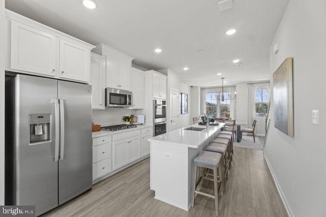 kitchen featuring white cabinets, a breakfast bar, stainless steel appliances, and an island with sink