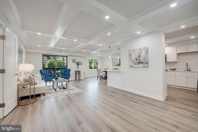 living room featuring coffered ceiling, crown molding, sink, light wood-type flooring, and beamed ceiling