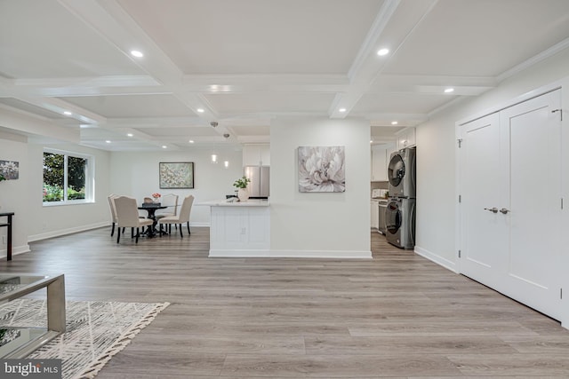 interior space featuring beam ceiling, stacked washing maching and dryer, and light hardwood / wood-style floors