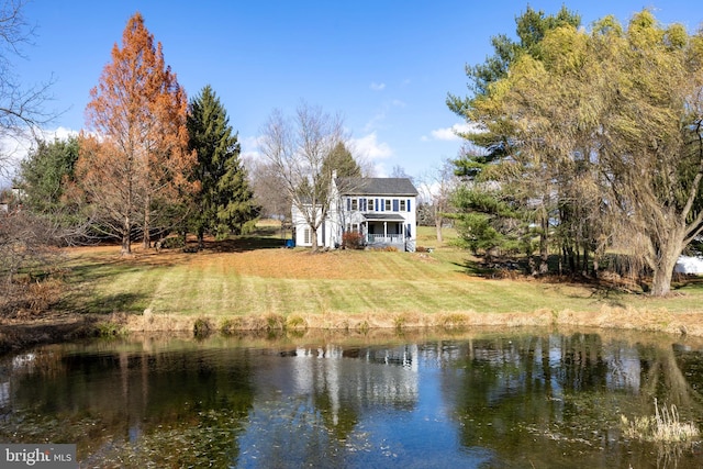 back of house with a yard and a water view