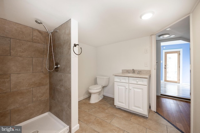 bathroom with hardwood / wood-style floors, vanity, toilet, and tiled shower