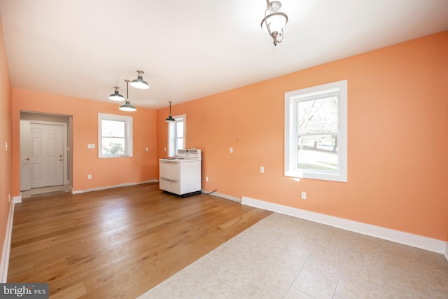 unfurnished living room featuring plenty of natural light, washer / dryer, and light wood-type flooring