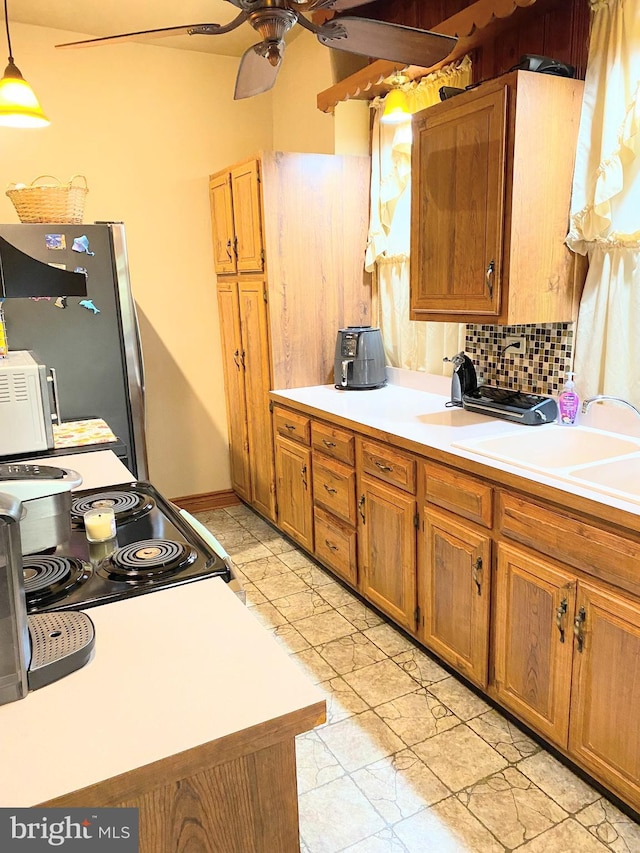 kitchen with pendant lighting, sink, range with electric cooktop, decorative backsplash, and stainless steel fridge